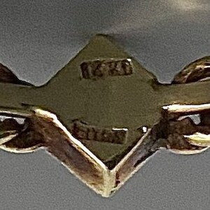May include: Close-up of a gold chain with a diamond-shaped tag that reads "16K" and "Gold".