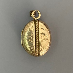 May include: A gold oval locket with a rope-like design down the center and floral engravings on the front.