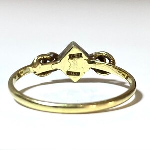 May include: A gold ring with a square-shaped gemstone in the center and two smaller gemstones on either side.