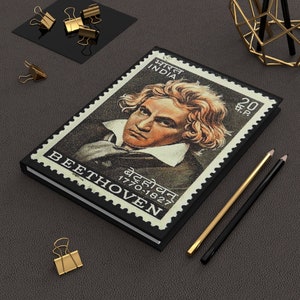 May include: A black notebook with a vintage stamp featuring a portrait of Beethoven. The stamp is from India and features the text "भारत INDIA" and "20 पैसे". The notebook also features the text "BEETHOVEN" and "बैठोवन 1770-1827".