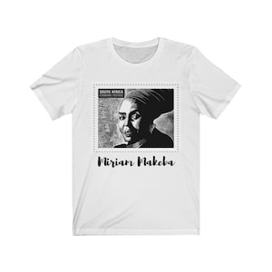 Peut inclure: Un t-shirt blanc avec une image en noir et blanc de Miriam Makeba sur un timbre-poste. Le timbre indique "South Africa Standard Postage". Le texte "Miriam Makeba" est imprimé sous l'image.