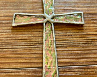 Peut inclure: Une croix en verre coloré avec un motif rose, vert et iridescent. La croix est en verre et a un cadre argenté.