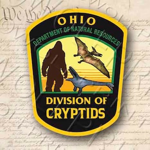 May include: A yellow and black patch with the text "Ohio Department of Natural Resources Division of Cryptids". The patch features a Bigfoot, a pterosaur, and a plesiosaur.