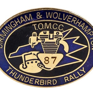 以下が含まれることがあります： 金色の縁と青と黒の中央部を持つ楕円形のピン。ピンには「BIRMINGHAM & WOLVERHAMPTON」と「THUNDERBIRD RALLY」の文字が記されています。中央には、車両の様式化された画像と数字「87」があります。