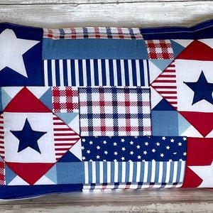 May include: A red, white, and blue patchwork pillow with stars and stripes. The pillow is made of different fabrics and has a blue border.