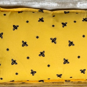 May include: A yellow throw pillow with a black bee pattern. The pillow is made of a soft, comfortable fabric and has a zipper closure.