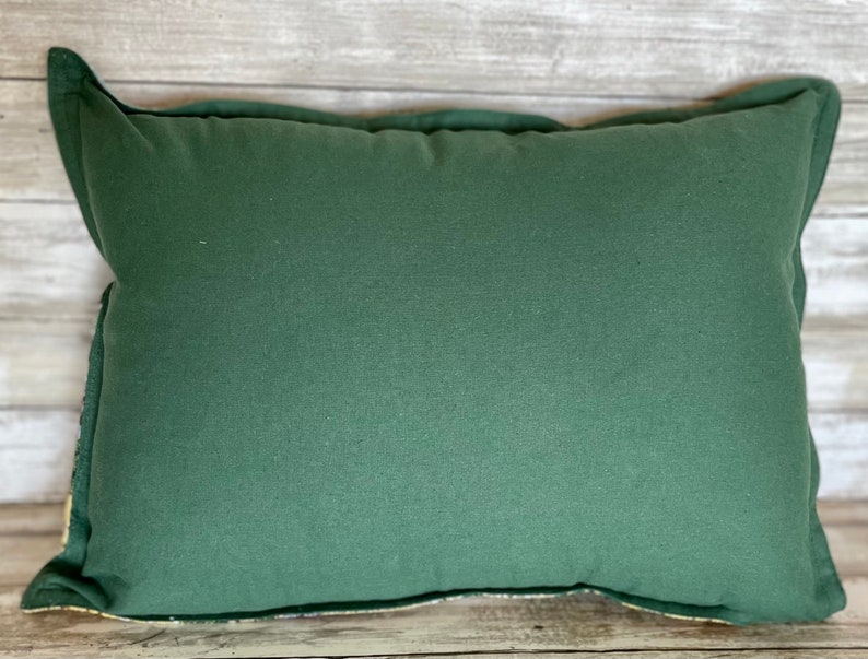 May include: A dark green pillow with a plain, solid color. The pillow is made of a soft, textured fabric.