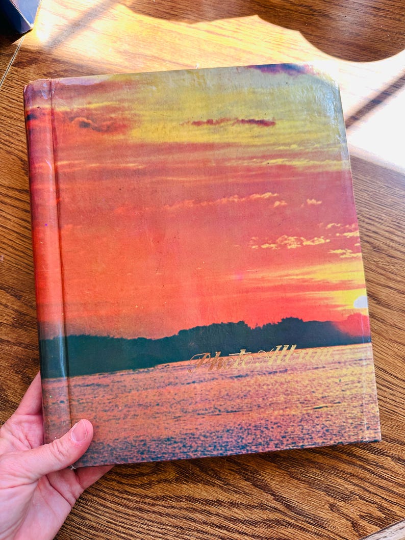 May include: A vintage hardback book with a sunset scene on the cover. The cover features a colourful sky with orange, yellow, and pink hues, and a dark silhouette of trees and water in the foreground. The book's title is visible in gold lettering at the bottom of the cover.