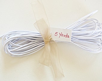 May include: A white elastic cord, tied with a beige ribbon, and labeled "5 yards".