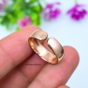 以下が含まれることがあります： シンプルなオープンエンドのローズゴールドのリング。リングは金属製で、滑らかで磨かれた仕上げになっています。