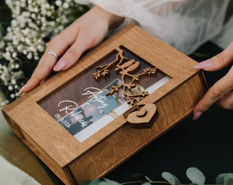 May include: A wooden keepsake box with a clear window, featuring a decorative bird and branch design. The box is engraved with the names "Antony & Rebecca" and the date "09.09.2024". The box is secured with a heart-shaped clasp.