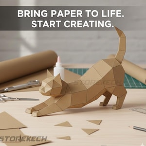 以下が含まれることがあります： 木製の表面で伸びをする幾何学的な紙の猫。テキストは「BRING PAPER TO LIFE. START CREATING.」猫は茶色の紙でできており、はさみ、接着剤、紙のロールなど、クラフト用品に囲まれています。Storekechのロゴが表示されます。