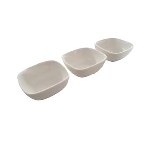 May include: Three off-white, square ceramic bowls are arranged in a row. The bowls have rounded corners and a slightly curved rim. The bowls are empty and appear clean. The background is plain white.
