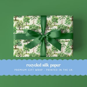 Könnte beinhalten: Ein Geschenk, verpackt in recyceltem Seidenpapier mit einem grünen Baummuster. Es ist mit einem dunkelgrünen Band und einer Schleife gebunden. Der Hintergrund ist einfarbig grün. Der Text unten lautet "recycled silk paper" und "PREMIUM GIFT WRAP - PRINTED IN THE UK."