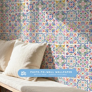 May include: A vibrant floral wallpaper with a repeating tile pattern. The design incorporates flowers in blue, pink, yellow, and green against a white backdrop. The text "PASTE-TO-WALL WALLPAPER" is visible, along with "BRITISH MADE".