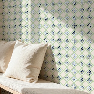 May include: A cream-colored wall with a repeating pattern of blue floral designs within green diamond shapes. Two off-white linen pillows rest on a wooden bench in the foreground, creating a cozy, inviting scene.