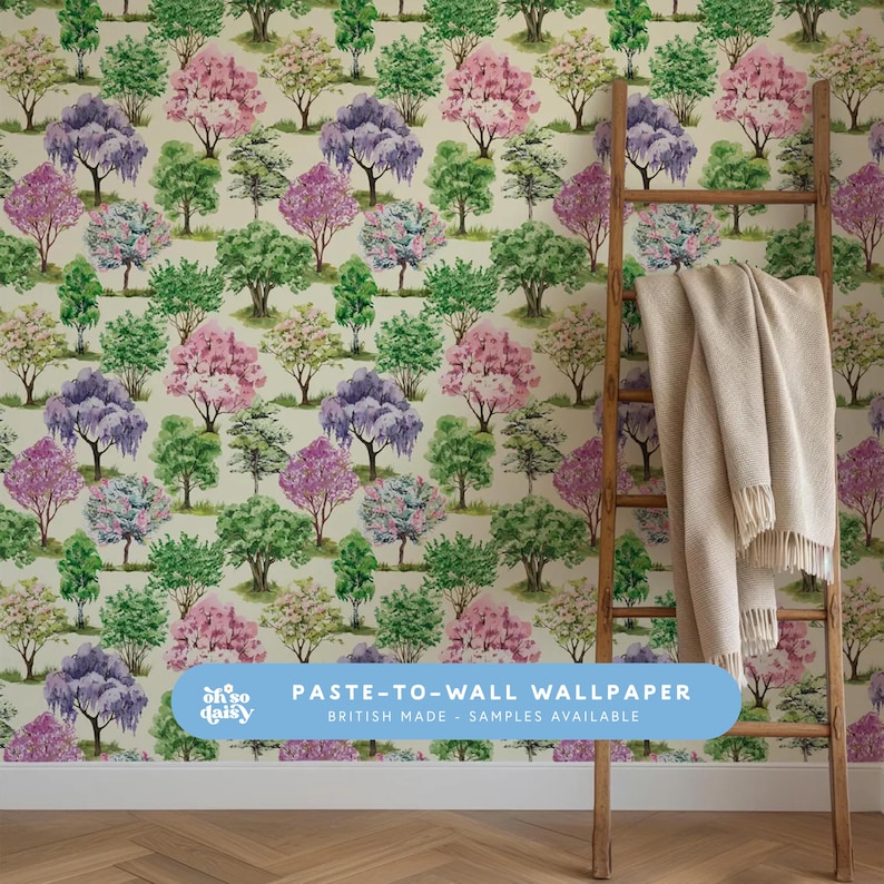 May include: Wallpaper featuring a repeating pattern of stylized trees in shades of green, pink, purple, and white against a cream background. A wooden ladder leans against the wall, with a beige blanket draped over it. The text "PASTE-TO-WALL WALLPAPER BRITISH MADE - SAMPLES AVAILABLE" is visible.