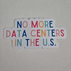 May include: A white sticker with the text "NO MORE DATA CENTERS IN THE U.S." in various colours. The sticker has a rounded, cloud-like shape and is likely for laptops, water bottles, or other items.
