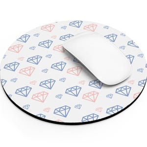 May include: A white computer mouse rests on a round mousepad. The mousepad has a black border and a repeating pattern of blue and pink diamond shapes on a white background. The mouse is white.