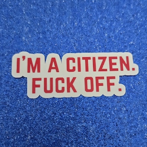 May include: A white sticker with red text that reads "I'M A CITIZEN. FUCK OFF." The sticker is rectangular with rounded corners and is set against a blue, textured background.