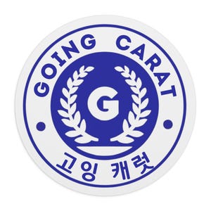 Peut inclure: Un autocollant rond avec une bordure blanche et un motif bleu. Le texte "GOING CARAT" est disposé en cercle autour d'un emblème central. L'emblème présente un "G" à l'intérieur d'une couronne de laurier, avec du texte coréen en dessous.