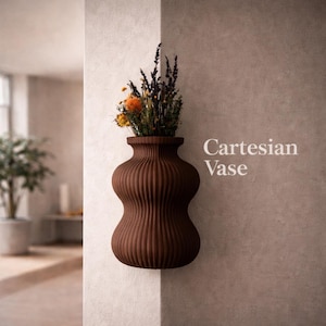 May include: A brown, ribbed, wall-mounted vase filled with dried flowers. The vase has a unique, curved shape and is labeled "Cartesian Vase" in white text. The flowers include orange and purple blooms.