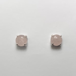 May include: A pair of silver stud earrings with round, pale pink rose quartz stones.