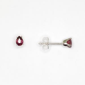 May include: A pair of silver stud earrings with pear-shaped pink gemstones.