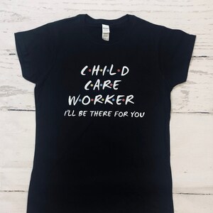 May include: Black t-shirt with the text "CHILD CARE WORKER I'LL BE THERE FOR YOU" in a stylised font with colourful dots.
