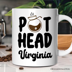 Pode incluir: Caneca de café de cerâmica branca com texto preto que diz "Pot Head Virginia" e uma ilustração preta e marrom de uma cafeteira.