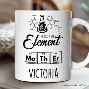 May include: White ceramic mug with a black design featuring a chemical flask, the words "The Essential Element", and the chemical symbols and names for Molybdenum, Thorium, and Erbium. The name "VICTORIA" is printed below the chemical symbols.
