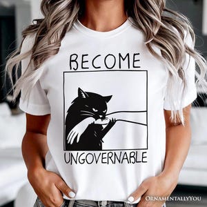 Camiseta "Conviértete en un gato negro ingobernable", meme humorístico que muerde la mano