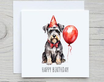 May include: A watercolor birthday card featuring a Schnauzer wearing a party hat and bow tie, holding a red balloon. The words "HAPPY BIRTHDAY" are printed below the dog in a simple font. The card is white with a white envelope.