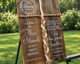 May include: A rectangular wooden sign featuring white text that reads The Johnsons June 28, 2025, A Cord of Three Strands Is Not Easily Broken, and So They Are No Longer Two But One Flesh, Therefore What God Has Joined Together, Let No One Separate.