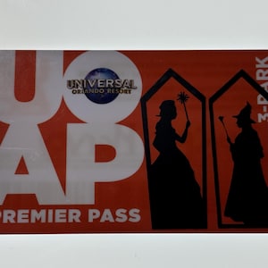 May include: A red and white Universal Orlando Resort Premier Pass card with the text "3-Park" in the top right corner. The card features a silhouette of two figures, one with a wand and the other with a crown.