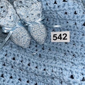 May include: A light blue crocheted baby blanket with two matching baby booties. The blanket has a textured pattern and the booties have white accents. The number 542 is written on a white tag.