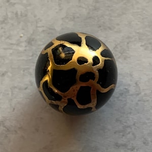 May include: Black sphere with a gold geometric pattern.