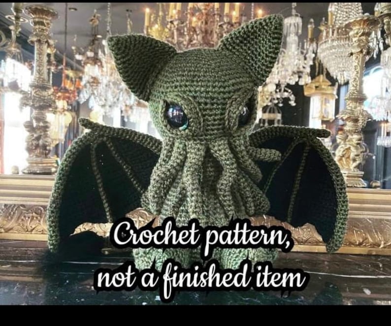 May include: Green crocheted Cthulhu plush toy with large eyes and wings. Crochet pattern, not a finished item.