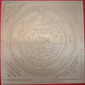 May include: A silver metal yantra with a fish symbol in the center and Sanskrit text surrounding it. The text includes the words "Om" and "Sri" and the phrase "Matsya Panaya Soma Kasura".