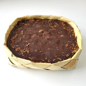May include: A block of dark brown palm sugar in a woven basket made of dried palm leaves.