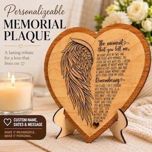 May include: A heart-shaped wooden memorial plaque with a wing design and a poem. The plaque includes the text "Personalizeable MEMORIAL PLAQUE" and "Custom Name, Dates & Message". A candle and flowers are in the background.