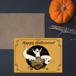 May include: A yellow card with a black border and a black bat silhouette at the top. The card says "Happy Halloween!" in black text. There are three white ghosts in a cauldron with a pumpkin on top. The cauldron is filled with brown liquid and there are brown nuts around the cauldron.