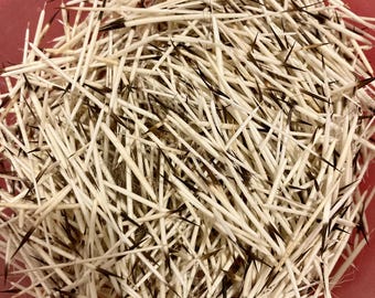 May include: A close-up shot of a pile of porcupine quills. The quills are primarily white with dark brown tips, creating a striking contrast. They are densely packed together, filling the frame. The quills are in a red container.