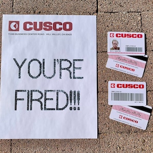 K&ouml;nnte beinhalten: Ein wei&szlig;es Blatt Papier mit den Worten "YOU'RE FIRED!!!" in Schwarz gedruckt. Es gibt vier rote und wei&szlig;e Mitarbeiterausweise mit dem Firmennamen "CUSCO" darauf gedruckt. Die Karten haben einen Barcode und den Namen des Mitarbeiters, "Martin McFly", darauf gedruckt.