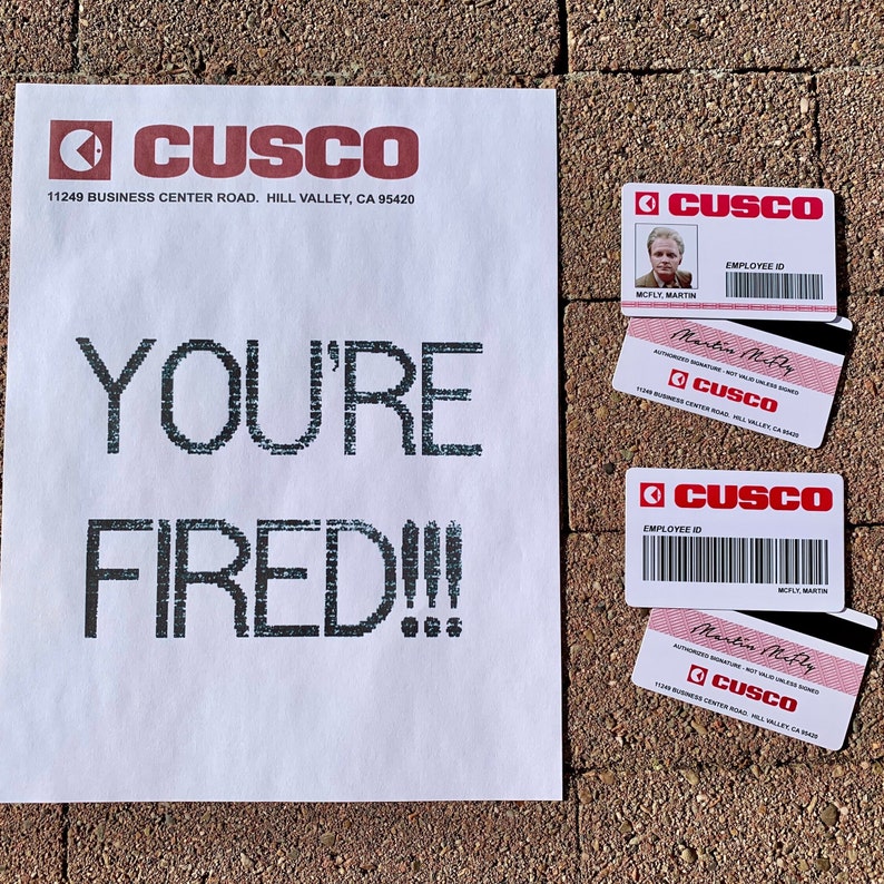 K&ouml;nnte beinhalten: Ein wei&szlig;es Blatt Papier mit den Worten "YOU'RE FIRED!!!" in Schwarz gedruckt. Es gibt vier rote und wei&szlig;e Mitarbeiterausweise mit dem Firmennamen "CUSCO" darauf gedruckt. Die Karten haben einen Barcode und den Namen des Mitarbeiters, "Martin McFly", darauf gedruckt.