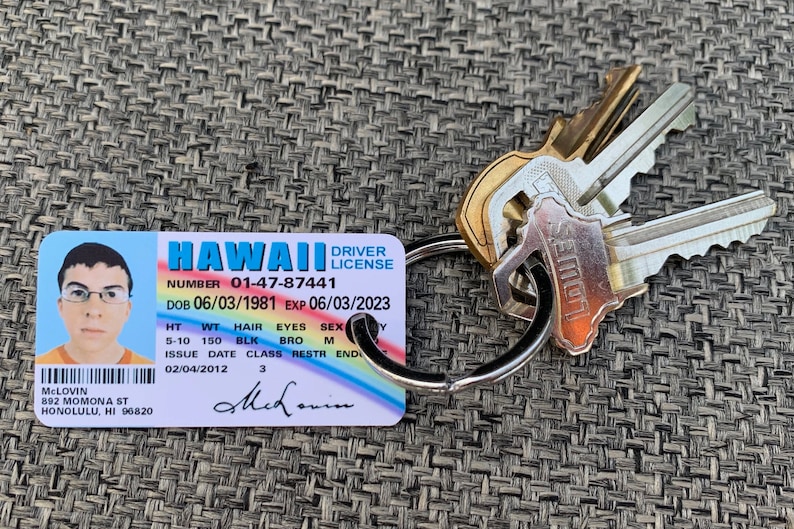 K&ouml;nnte beinhalten: Ein hawaiianischer F&uuml;hrerschein mit dem Namen McLovin und einem Foto, befestigt an einem Schl&uuml;sselring mit mehreren Schl&uuml;sseln. Der F&uuml;hrerschein enth&auml;lt Details wie Geburtsdatum, Gr&ouml;&szlig;e und Ablaufdatum.