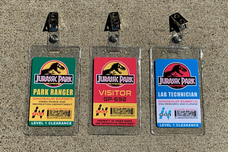 Puede incluir: Tres identificaciones de Jurassic Park con diferentes t&iacute;tulos: Park Ranger, Visitor y Lab Technician. Cada identificaci&oacute;n tiene un soporte de pl&aacute;stico transparente y un clip met&aacute;lico. Las identificaciones muestran el logotipo de Jurassic Park y texto.