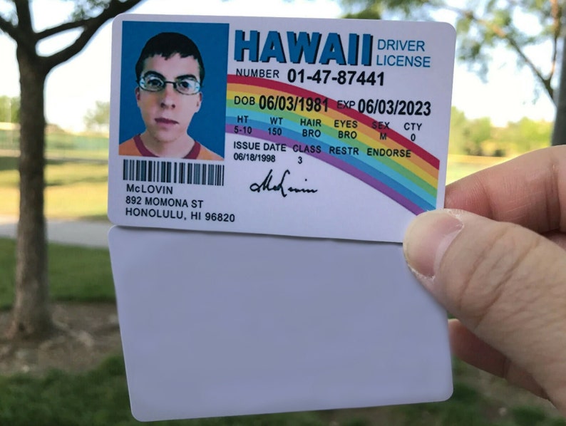 K&ouml;nnte beinhalten: Ein hawaiianischer F&uuml;hrerschein mit dem Namen McLovin, Geburtsdatum 03.06.1981 und Ablaufdatum 03.06.2023. Der F&uuml;hrerschein zeigt ein Foto einer Person mit Brille und einem orange-roten Hemd. Der F&uuml;hrerschein enth&auml;lt auch ein Regenbogen-Design.