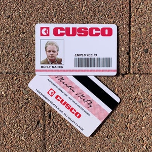 K&ouml;nnte beinhalten: Ein wei&szlig;er Plastik-Mitarbeiter-Ausweis mit einem roten CUSCO-Logo. Die Karte zeigt ein Foto eines Mannes, den Namen "MCFLY, MARTIN" und einen Barcode. Die Karte hat au&szlig;erdem eine rote Signaturzeile mit dem Text "AUTHORIZED SIGNATURE - NOT VALID UNLESS SIGNED" und die handschriftliche Unterschrift "Martin McFly".