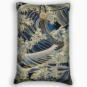 Op de afbeelding: Rechthoekig kussen met een Japans golfpatroon in blauw, zilver en goud. Het heeft een houten knoopsluiting met een zwart koord. Het patroon toont gestileerde golven, wat een textuur en gedetailleerde uitstraling geeft.